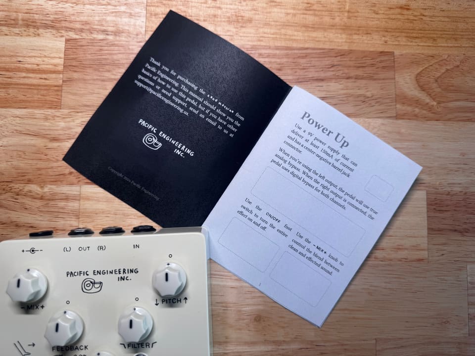 The printed manual included with the Sand Machine, open to its Power Up page next to the pedal